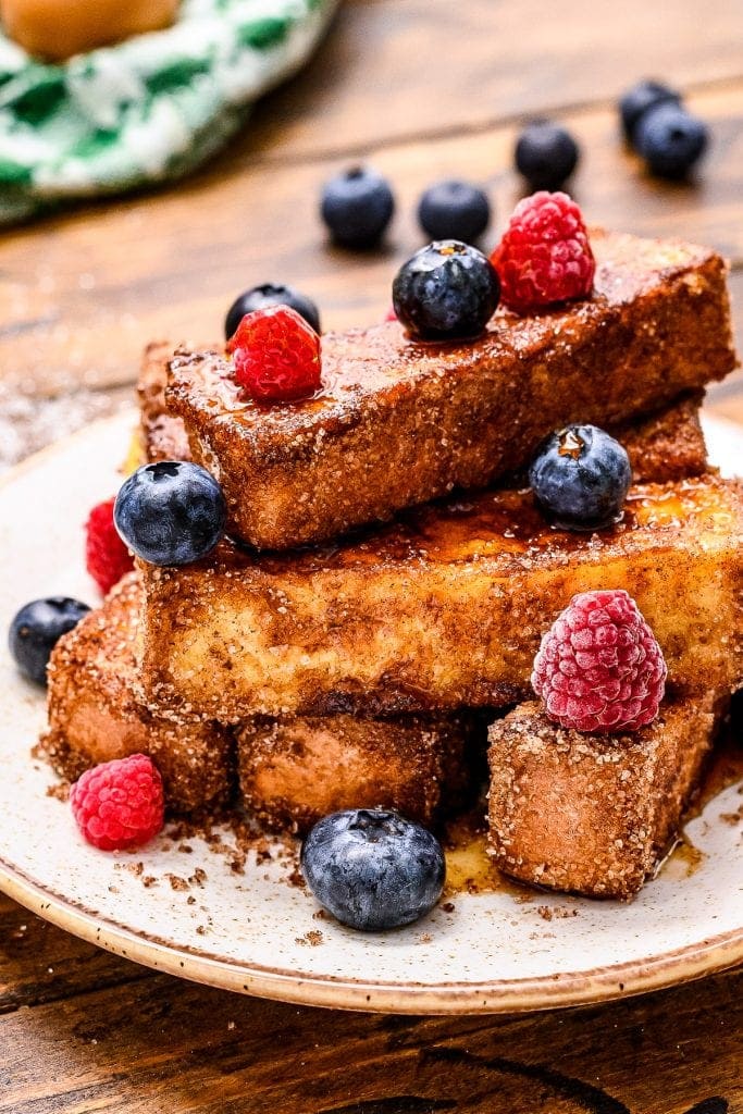 Plate with french toast sticks on it and blueberries and rasperries