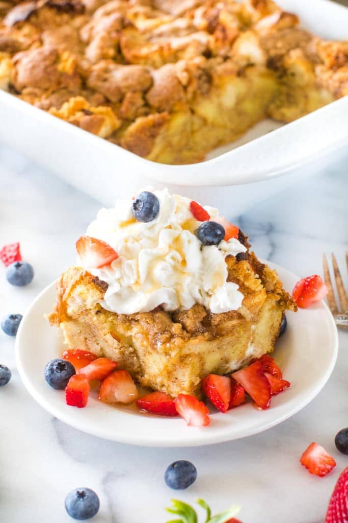 Overnight French Toast Casserole on plate with whipped cream and berries