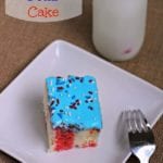 A piece of patriotic poke cake on a white square plate with a fork next to a glass of milk