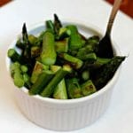 A white bowl of skillet asparagus with a fork in it sitting on a white plate