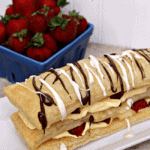 Easy strawberry napoleon on a long white plate with a crate of strawberries in the background