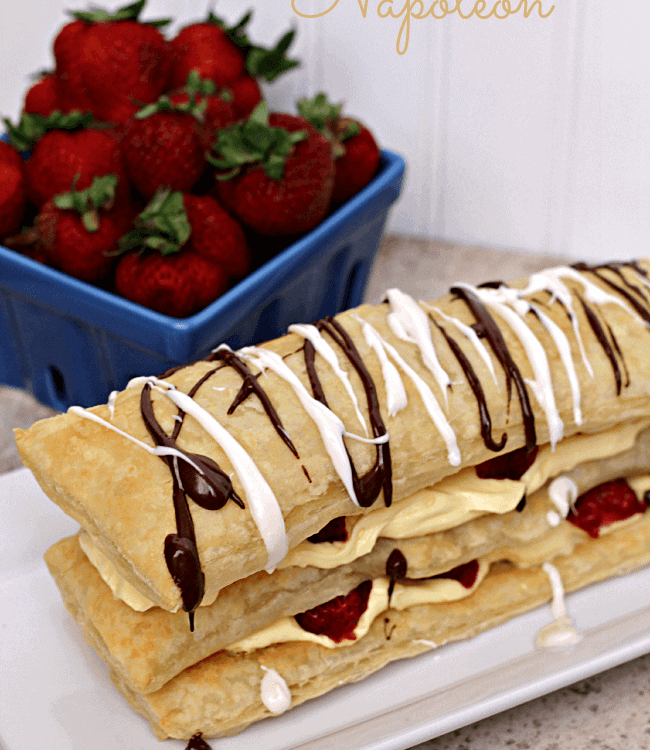 Easy strawberry napoleon on a long white plate with a crate of strawberries in the background