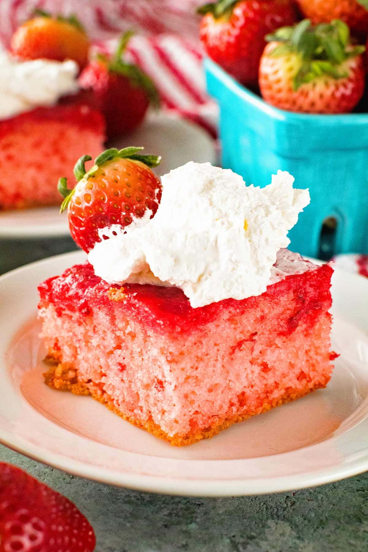 Upside Down Strawberry Cake on white plate with cool whip and strawberry garnish