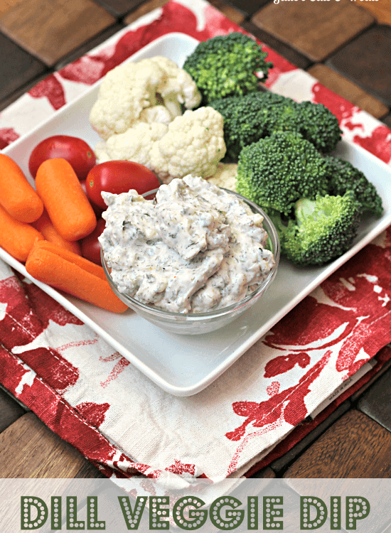 A square white plate with carrots, cherry tomatoes, cauliflower, broccoli, and a bowl of dill veggie dip on it