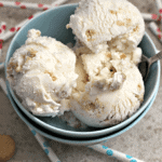 A bowl of golden Oreo ice cream with a spoon in it sitting on a counter with polka dot straws