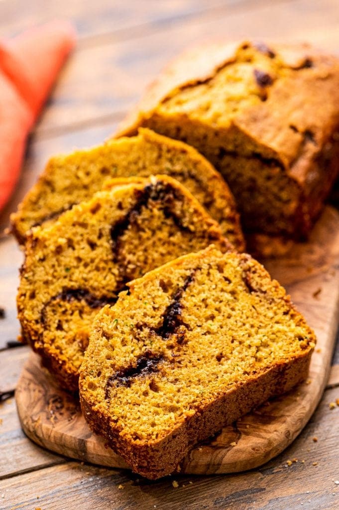 Pumpkin Zucchini Bread Recipe slice don a wooden cutting board.