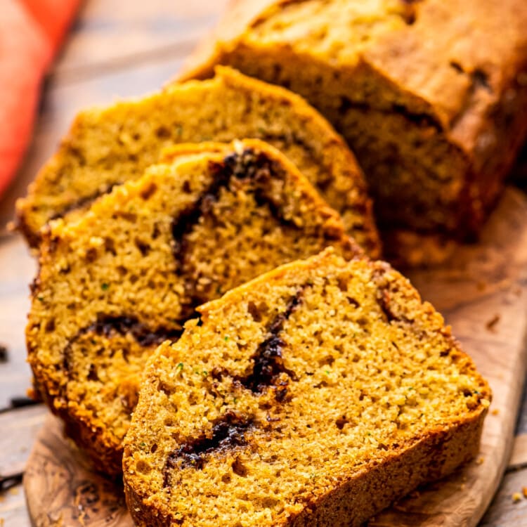 Pumpkin Zucchini Bread Recipe slice don a wooden cutting board.