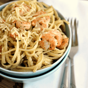 Two blue bowls stacked on a white napkin with the top one full of garlic butter shrimp scampi