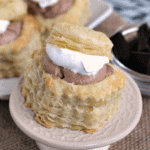 A french silk puff on a small white stand in front of more puffs on a white plate