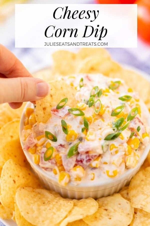 Hand dipping a tortilla chip into Cheesy Corn Dip