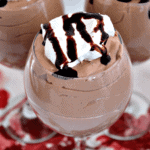 Three wine glasses of mint chocolate chip mousse topped with whipped cream and chocolate sauce