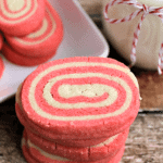 Stack of peppermint pinwheels on a table with a jar of milk and a plate of pinwheels