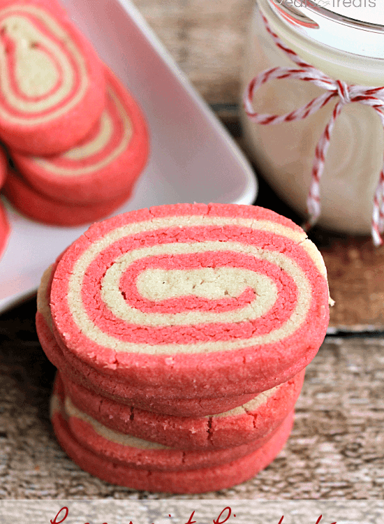 Stack of peppermint pinwheels on a table with a jar of milk and a plate of pinwheels
