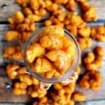 Glass jar of cheesy caramel puff corn spilling out onto the table