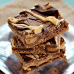 Three peanut butter and chocolate reese's cookie bars stacked on a metal plate