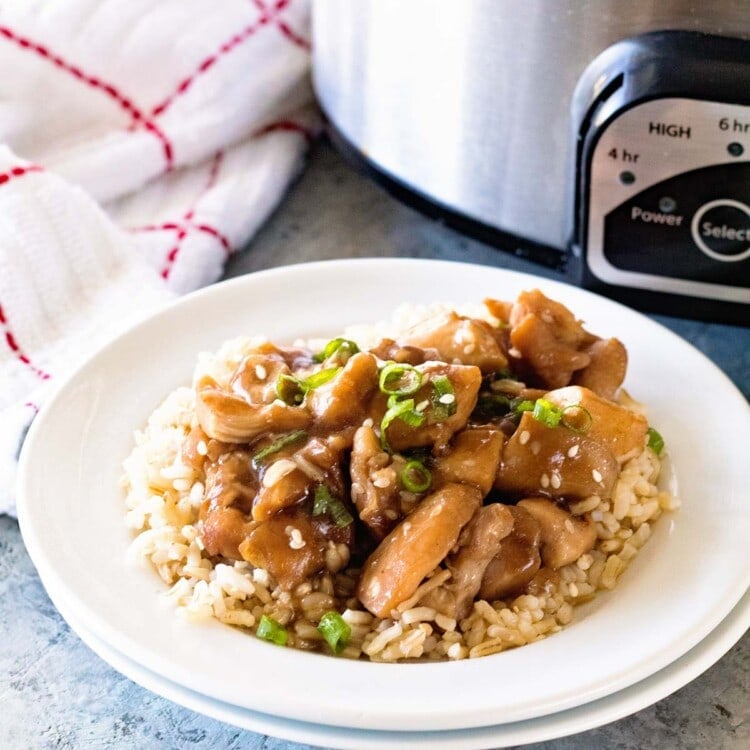 Slow Cooker Chicken Teriyaki over rice in a white bowl in front of a crock pot