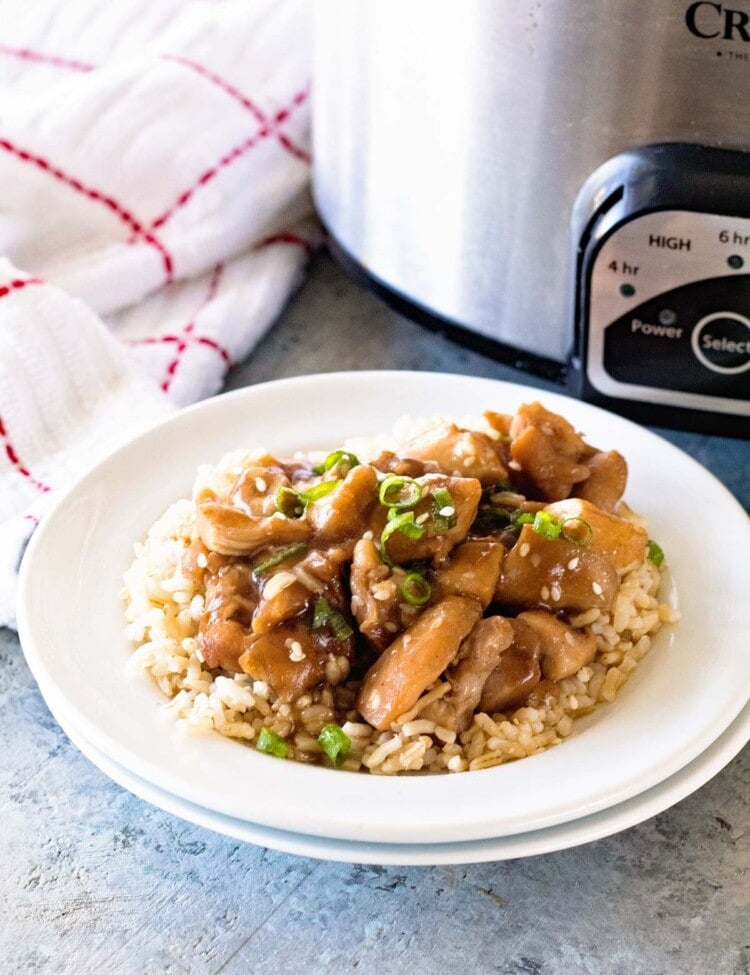 Slow Cooker Chicken Teriyaki over rice in a white bowl in front of a crock pot