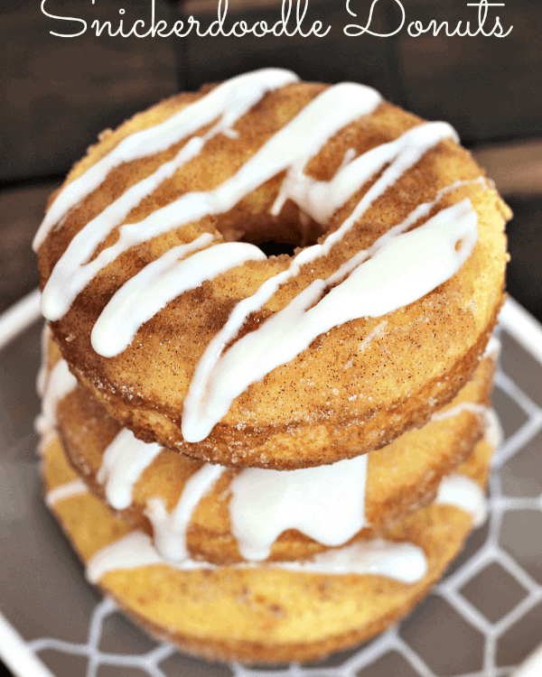 Three drizzled snickerdoodle donuts stacked on a brown and white plate