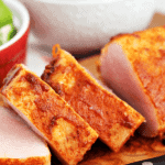 Slices of southwestern pork tenderloin on a cutting board with a knife