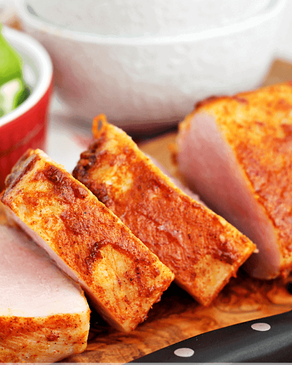 Slices of southwestern pork tenderloin on a cutting board with a knife