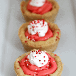 Strawberry sugar cookie cups in a row on a white plate