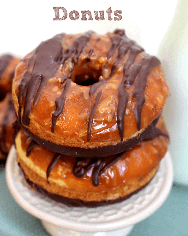 Two baked samoa donuts stacked on a small white stand