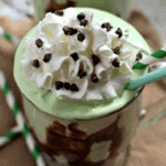 Two glass mugs of grasshopper ice cream dessert topped with whipped cream and mini chocolate chips