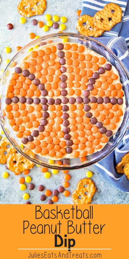 Peanut butter dip with candies on top making it look like a basketball in a clear glass pie plate on a counter next to pretzels and candies with an orange banner across the bottom reading basketball peanut butter dip in black text