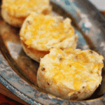 Three loaded potato bombs in a row on a silver serving tray