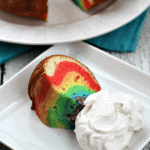 Rainbow cloud cake slice on a square white plate with whipped cream