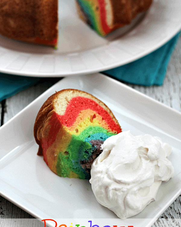 Rainbow cloud cake slice on a square white plate with whipped cream