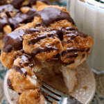 Samoa monkey bread muffin on a small white stand with a fork next to a pitcher of milk