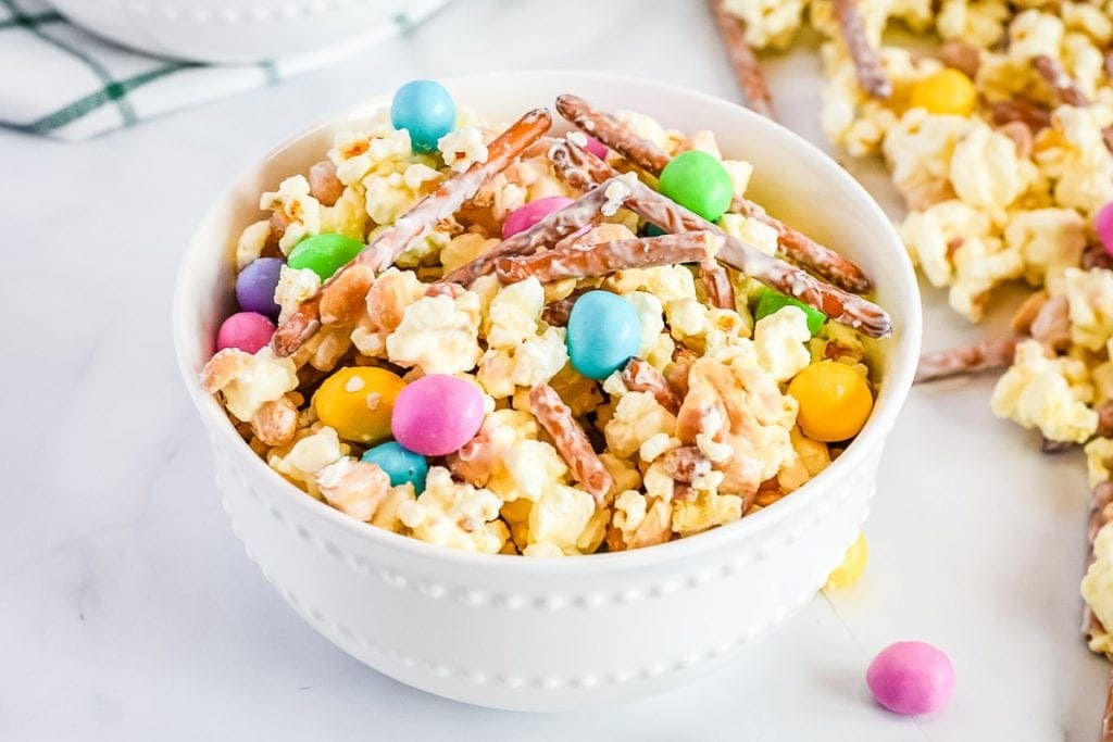 White bowl with prepared bunny bait snack mix on marble background