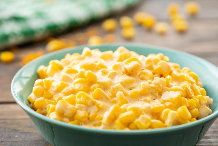 An aqua colored bowl with creamed corn in it.