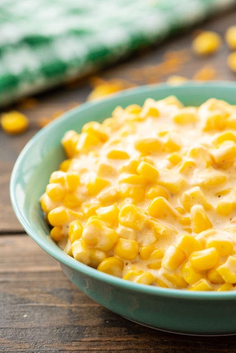 Creamed corn in a aqua colored bowl on a wooden background