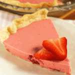 Slice of creamy strawberry pie on a white plate with slices of fresh strawberry on top