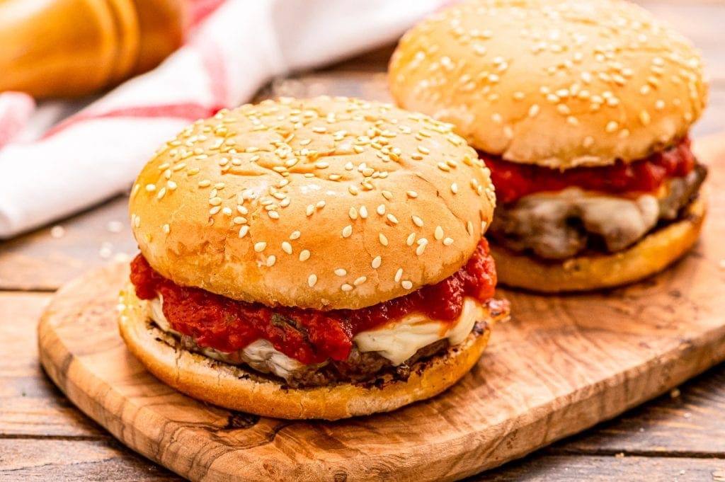 Italian Burger on a bun sitting on a wood cutting board