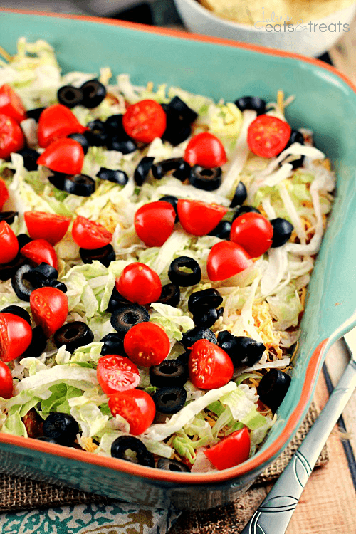 Easy Taco Dip Logo ~ Everyone Will Dig Into this Festive Taco Dip! Loaded with Sour Cream, Taco Seasoning, Salsa, Cheese, Lettuce, Tomatoes & Black Olives!