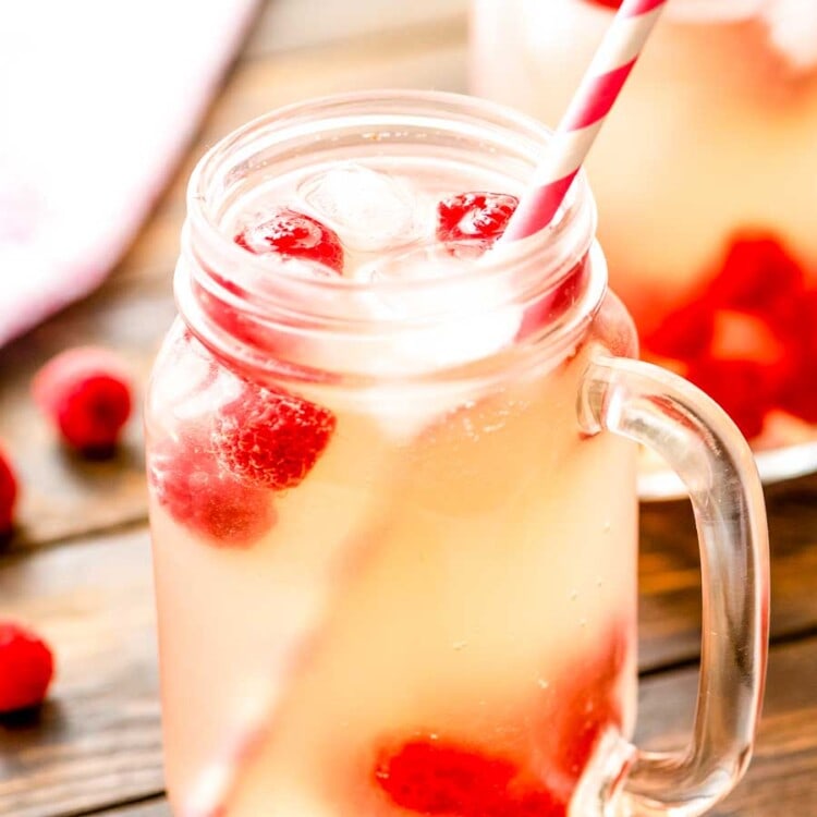 Moscato Lemonade in a mason jar with ice, raspberries, and a straw