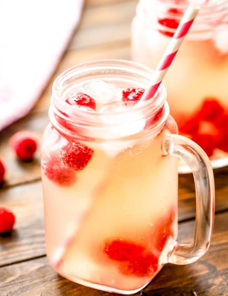 Moscato Lemonade in a mason jar with ice, raspberries, and a straw