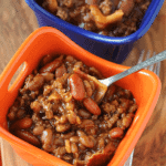 An orange and a blue bowl of crock pot hickory smoked baked beans