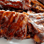 Several racks of smokey barbecue ribs on a white plate