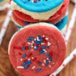 Stack of patriotic sugar cookie ice cream sandwiches on a wood table with red, white, and blue straws
