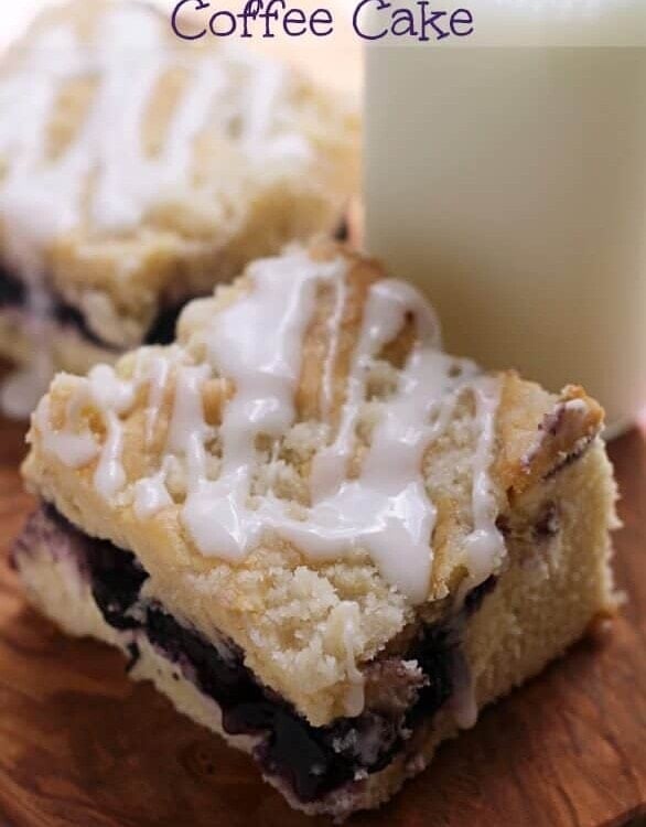 Two pieces of blueberry cream cheese coffee cake on a wood board with a glass jar of milk