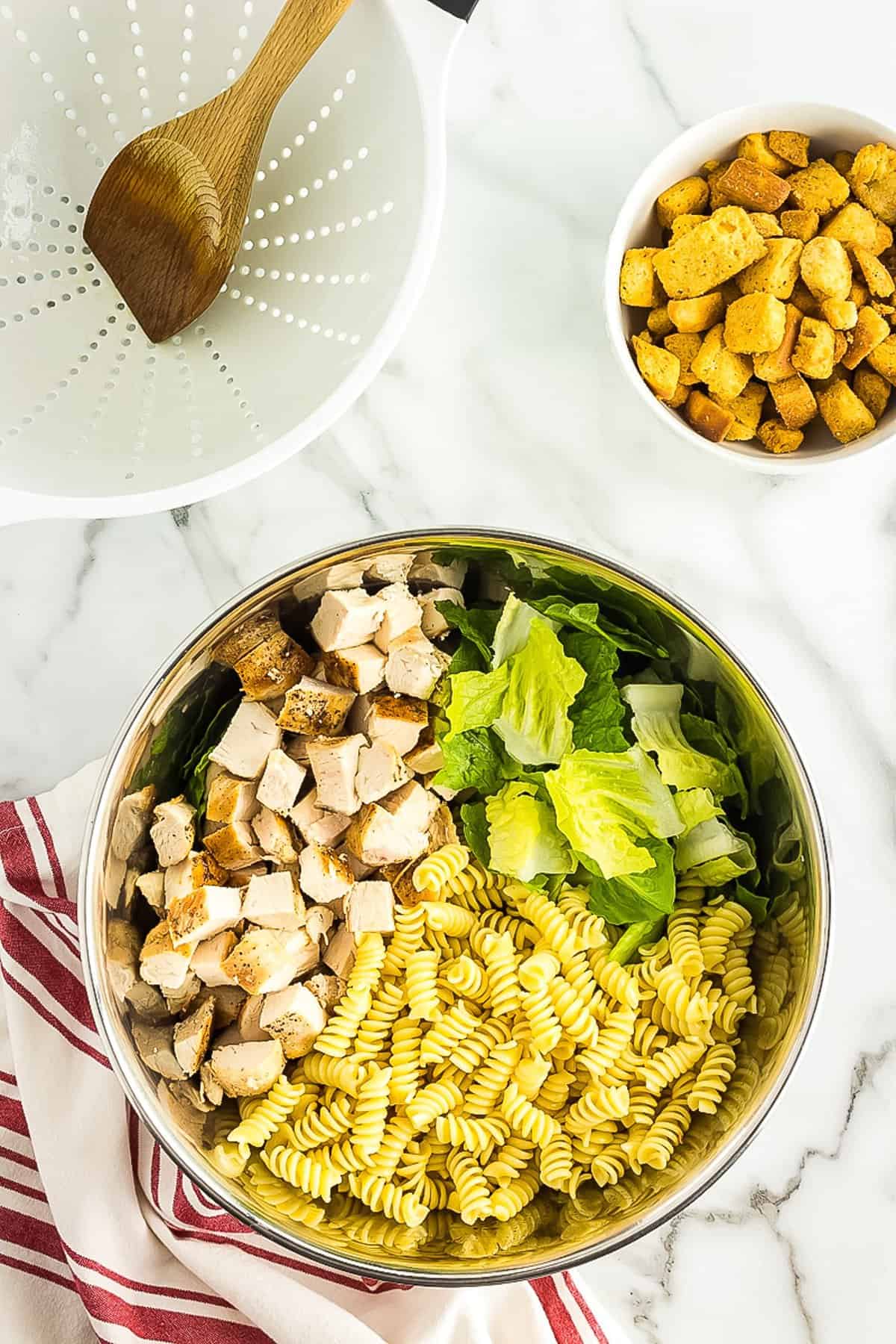 Ingredients in bowl for Caesar pasta salad before mixing