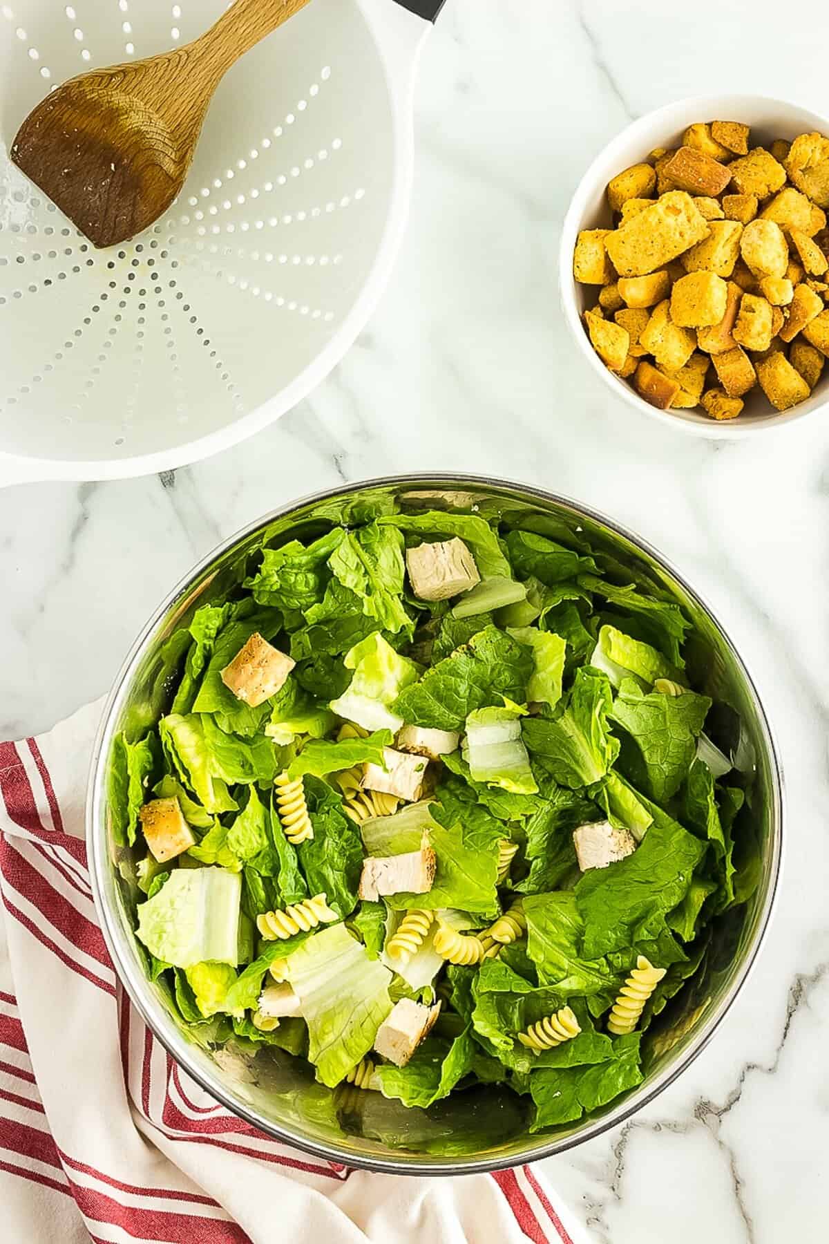 Caesar salad tossed in mixing bowl