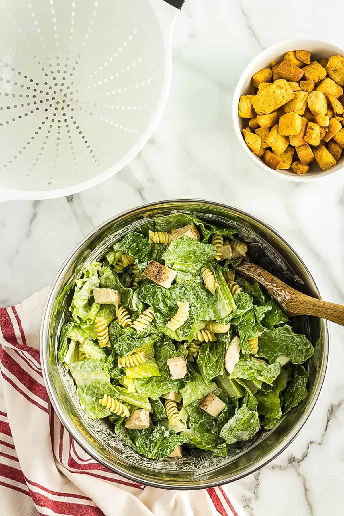 Tossed Caesar pasta salad in mixing bowl