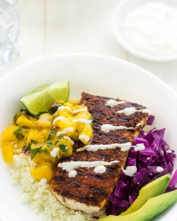 Fish taco bowl containing fish, avocado, limes, cabbage, and rice
