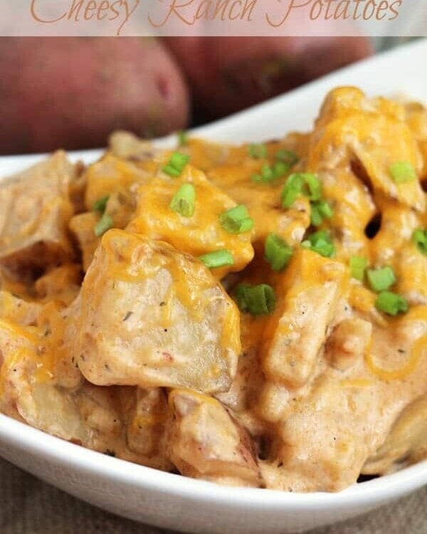 Crock pot cheesy ranch potatoes in a white bowl topped with chives