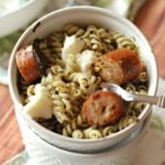 Two white bowls stacked with the top full of Pesto ricotta pasta